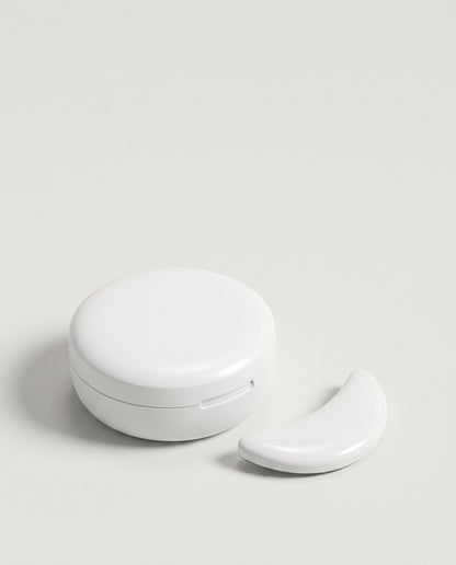 The closed round charging case with one unlit under-eye pad beside it