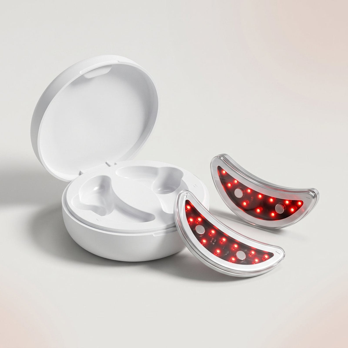 Open white charging case with two red light under-eye pads beside it