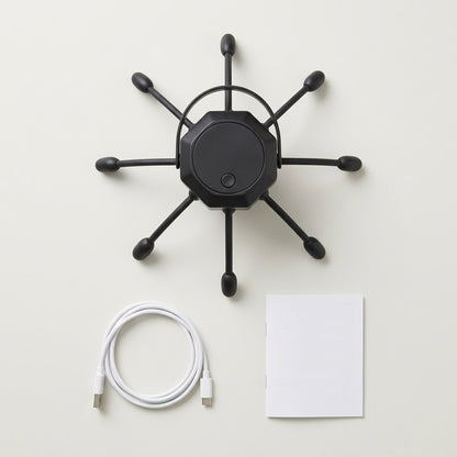 Overhead flat lay of the black scalp massager, charging cable and user manual