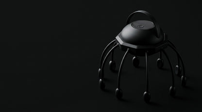 The black scalp massager lit against a black background