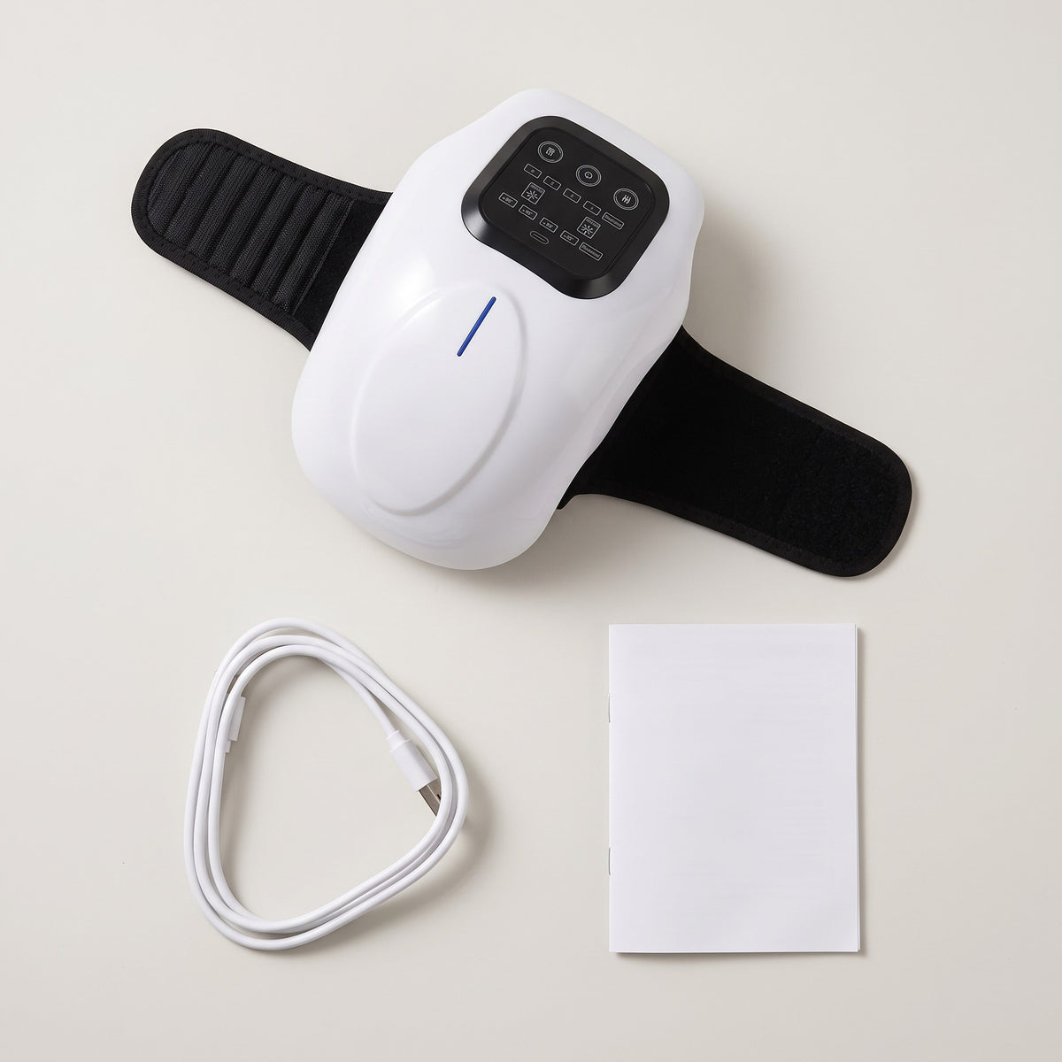 Flat lay of the joint massager, USB cable and user manual